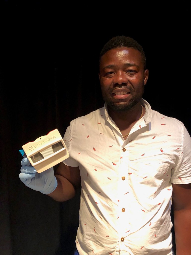 Dodji, a Museum Visitor, holds a white View Master.